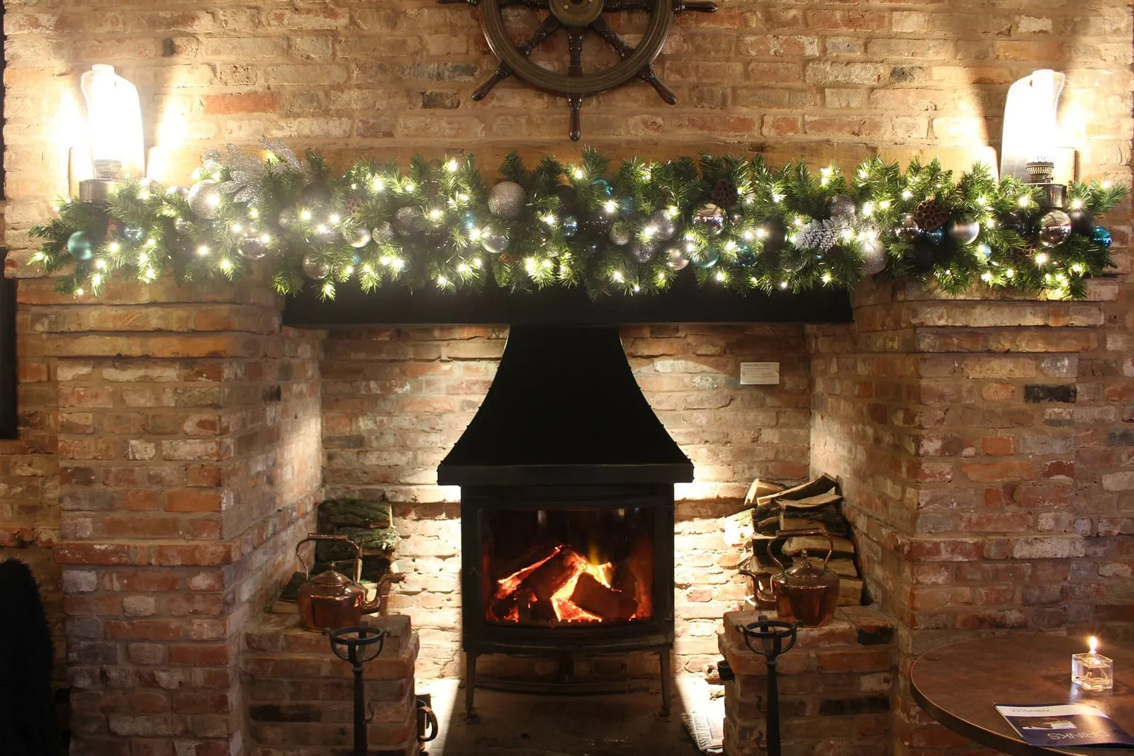 Brick fireplace with a lit Christmas garland above a log burner