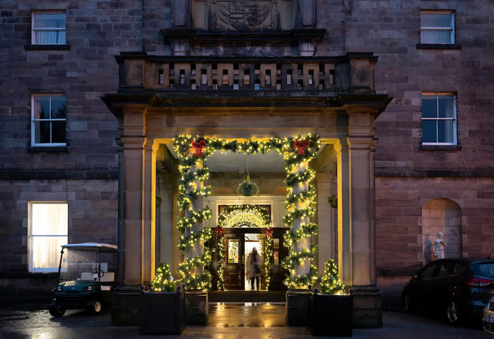 Country house doorway dressed with lit garland and red bows